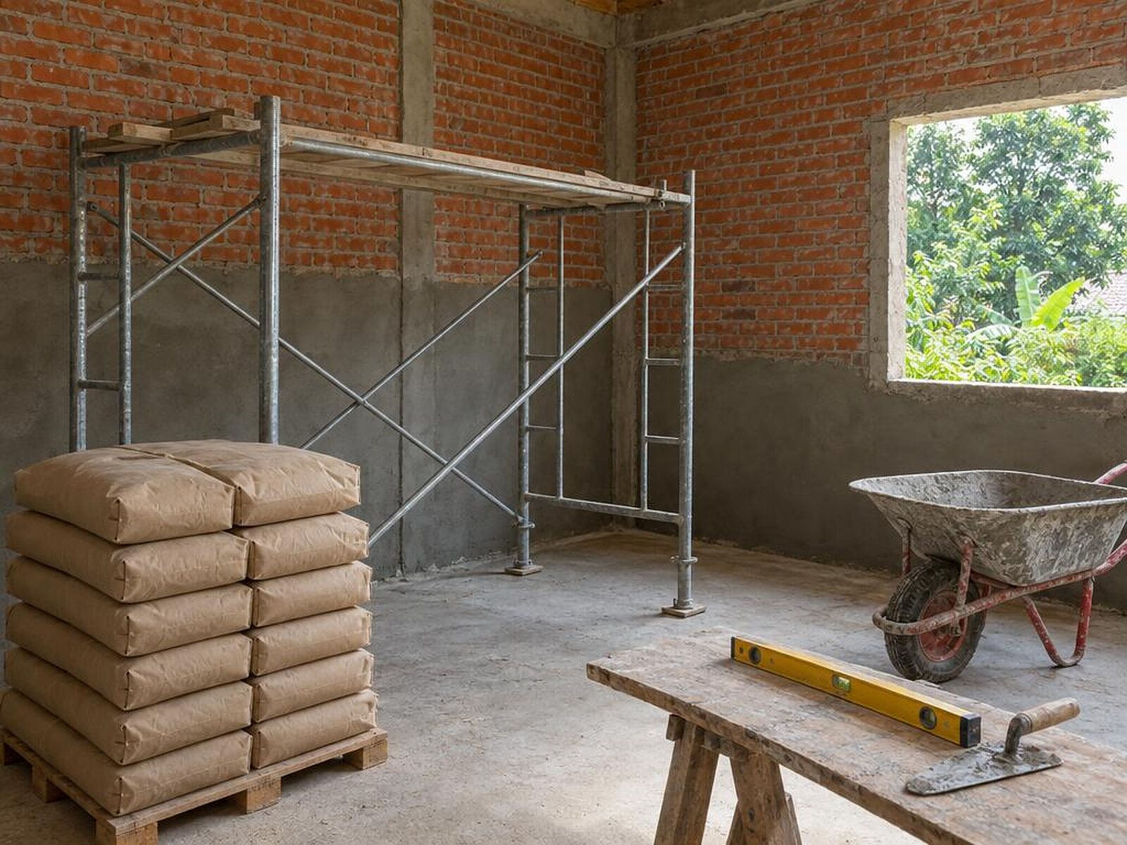 Ruangan dalam proses renovasi dengan dinding bata dan perancah